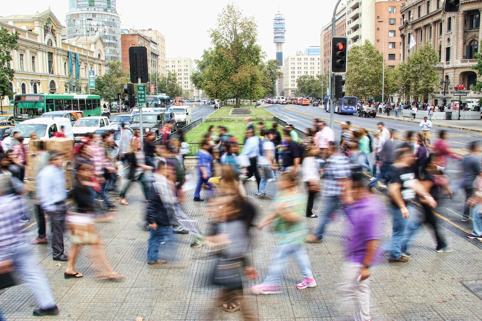 Large crowd walking through city, motion blurred.